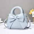 Light blue elegant handbag featuring a large bow and adjustable gold buckle strap - Blue