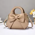 Light brown leather tote bag featuring a large bow design and gold hardware accents - Khaki