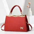 Red saffiano leather tote bag with gold bow ornament and adjustable crossbody strap - Burgundy
