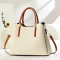 Close-up of beige woven texture handbag with brown leather handles and gold metal hardware - Off White