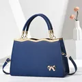 Minimalist navy blue leather tote bag with gold bow detail and metallic handles - Blue