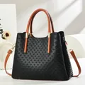 Detail of black woven texture handbag with contrasting brown straps and gold hardware - Black