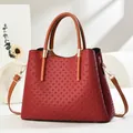 Detail of red trapezoid handbag with embossed weave texture and brown handles - Wine Red