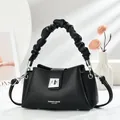Detalle de bolso en cuero negro con asa fruncida y cierre giratorio de plata fina - Negro