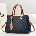 Close-up of dark blue woven texture on shoulder bag with brown leather handle details - Blue
