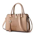 Sac cabas beige effet crocodile avec logo V doré et pompon sur fond blanc épuré - Kaki