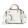 Close-up of white leather handbag with golden logo and cute cat-shaped coin purse charm - Off White