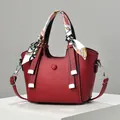 Detail der roten Handtasche mit Litschi-Muster, buntem Seidentuch und silberner Schnalle - Weinrot
