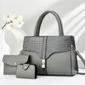 Three-piece grey tote set with crocodile texture and gold lock in a minimalist setting - Three-Piece Set / Gray