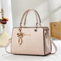 Detalle de bolso de cuero texturizado rosa claro con colgante de perla y logo dorado - Rosa