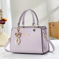 Detalle de un bolso Saffiano lila con herrajes dorados y colgante de perlas blancas - Morado