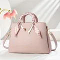 Detail of light pink pebble leather handbag with silk scarf handle and V-shaped charm - Pink