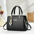 Primer plano de bolso negro con textura de grano cruzado y elegante colgante de perlas - Negro