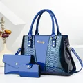 Detailed view of dark blue 3-piece bag set with snakeskin texture and metal logo - Blue