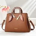 Detail of brown litchi pattern leather handbag with gold metal accents and silk scarf - Earthy Yellow