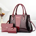 Close-up of burgundy three-piece bag set with snakeskin texture and polished finish - Red