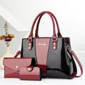 Close-up of a 3-piece set featuring patent leather tote and clutch with gold hardware - Wine Red