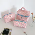 Detailed set of three red checkered makeup bags with light blue bow patterns on a desk - S / Red