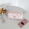 Close-up of pink checkered quilted pencil case with red bow patterns and brand label - Pink Plaid
