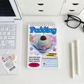 Spiraalnotitieboek met retro pudding illustratie op een bureau met kantoorspullen - Wekelijkse Planning - Dessert Taart