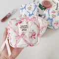 Detailed macro view of quilted floral makeup bag featuring elegant ribbon zipper pull - Pink