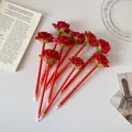 Vue de dessus de stylos bille en forme de rose rouge sur un bureau blanc chic - Rouge