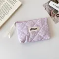 Detailed macro of lavender quilted fabric pouch with white ink splatter and brand tag - Purple