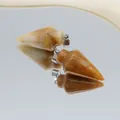 Arrowhead yellow jasper stone pendants with silver metal bails on a mirror surface - Topaz