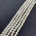 Strands of 6-8mm white natural freshwater pearls with radiant luster on dark background - 12-13mm / White