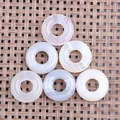Detailed view of six polished natural agate donut charms on a rustic woven background - Agate