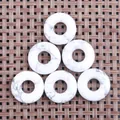 Macro detail of six white howlite stone donut pendants with natural grey veins on a woven mat - Howlite