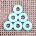Blue-green synthetic turquoise donut pendants with black mesh texture on woven mat - Turquoise