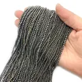Strand of 2mm faceted grey pyrite beads for jewelry making held in palm for scale - Hematite