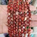 Hand holding polished teardrop Red Jasper stone beads for DIY jewelry making - Rainbow Stone
