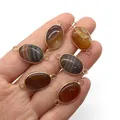 Detailed view of six striped agate oval pendant connectors held in hand for jewelry DIY - Striped Agate Oval Style / White