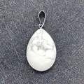 Teardrop-shaped white turquoise pendant with silver bail on gray background - Howlite