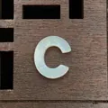 Macro view of natural white mother of pearl letter C bead with iridescent luster detail - Letter C