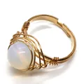 Bague artisanale avec grande pierre blanche irisée et fil doré entrelacé - Opale