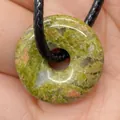 Unakite Donut Anhänger am schwarzen Band in der Hand zur Darstellung von Größe und Textur - Unakit
