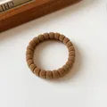 Elastisches Haargummi in Dunkelkhaki mit Rippenstrick-Struktur auf weißer Oberfläche - Ingwergelb