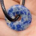 Natural snowflake blue stone donut pendant necklace with black braided rope in hand - Blue Spot Stone