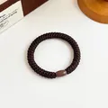 Elastico per capelli intrecciato marrone scuro con perla oliva liscia su sfondo bianco - Marrone scuro