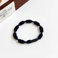 Minimalist black elastic hair tie with knotted texture and a sleek cylindrical clasp - Black
