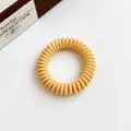 Matte mustard yellow spiral phone cord hair tie in a minimalist aesthetic setting - Yellow