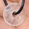 Natural white crystal donut pendant necklace with black cord held in hand - Transparent Crystal