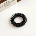 Elastico per capelli a spirale nero lucido su superficie minimalista beige - Nero