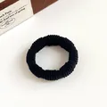 Elastic black fabric hair tie with rib texture on a minimalist cream background - Black