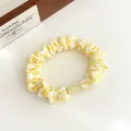 Yellow and white checkered fabric scrunchie with light green bead on white background - Yellow