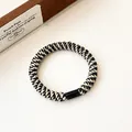 Elastic hair tie featuring a black and beige spiral woven pattern with a secure black clasp - Black