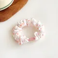 White fabric scrunchie with soft pink polka dots and elegant ruffled texture - Orange